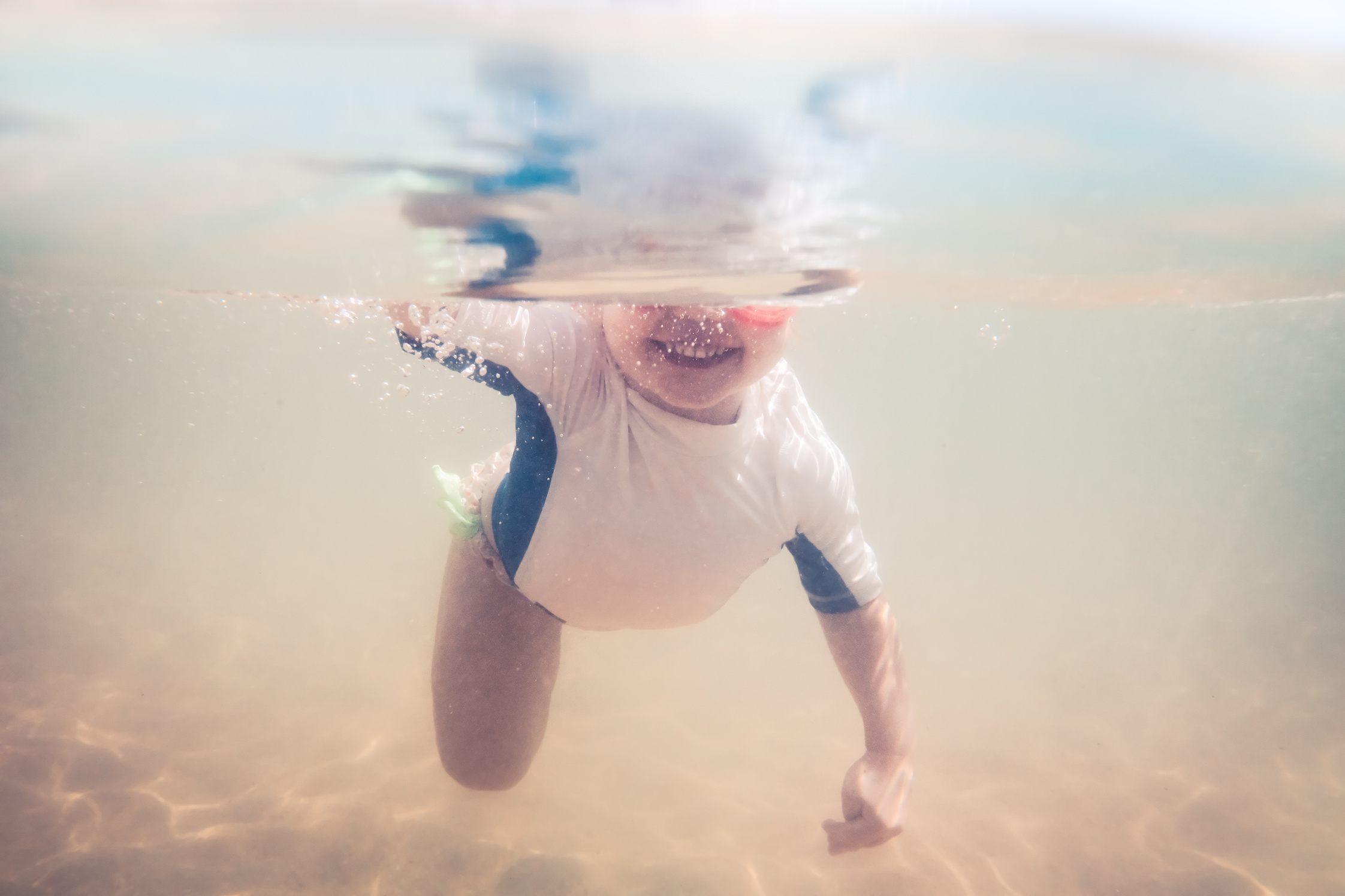 Happy child toddler swimming underwater during summer beach holidays vacation